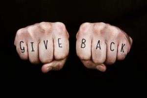 Two fists with the words "Give Back" written on the outside of the fingers,