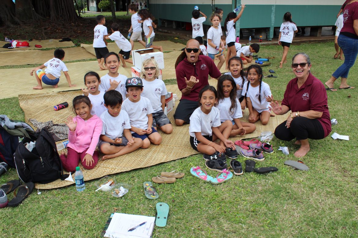 A group of young kids has been separated in a group awaiting games and smile for the camera.