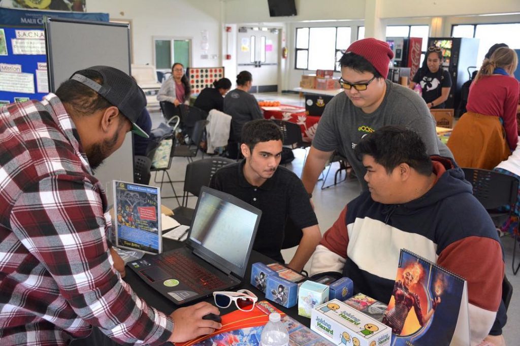 Strategic Gaming Society chat at their table, which is set up with gaming items.