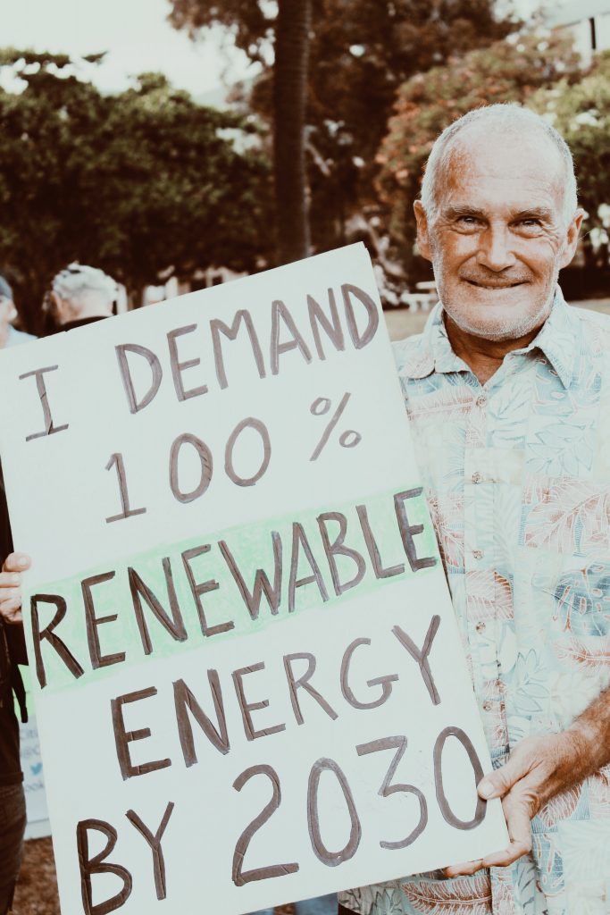 A kupuna holding a sign advocating for climate change.