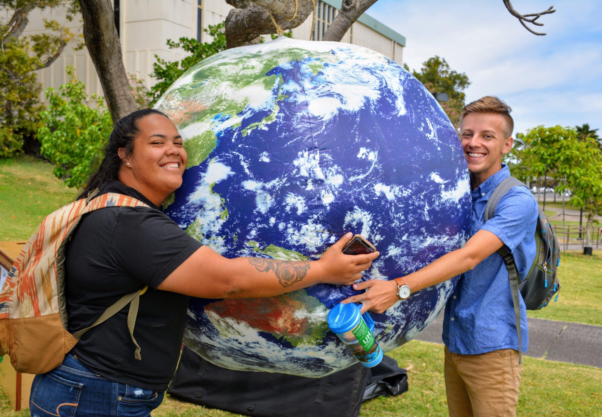 Two students hugging a inflatable globe