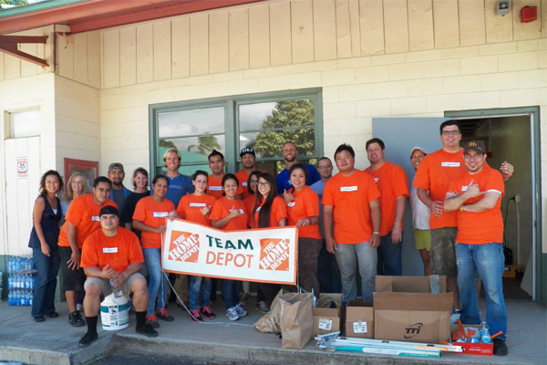 Group of volunteers holding a Team Depot Sign outside of the VRC building